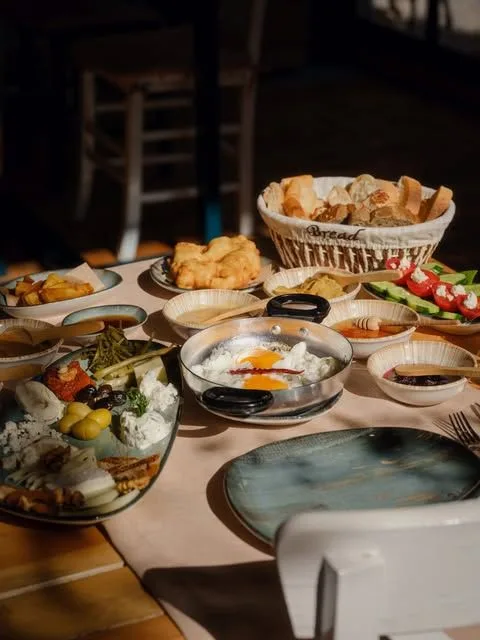 Zeytin, yumurta ve ekmek sepetiyle dolu geniş bir kahvaltı masası
